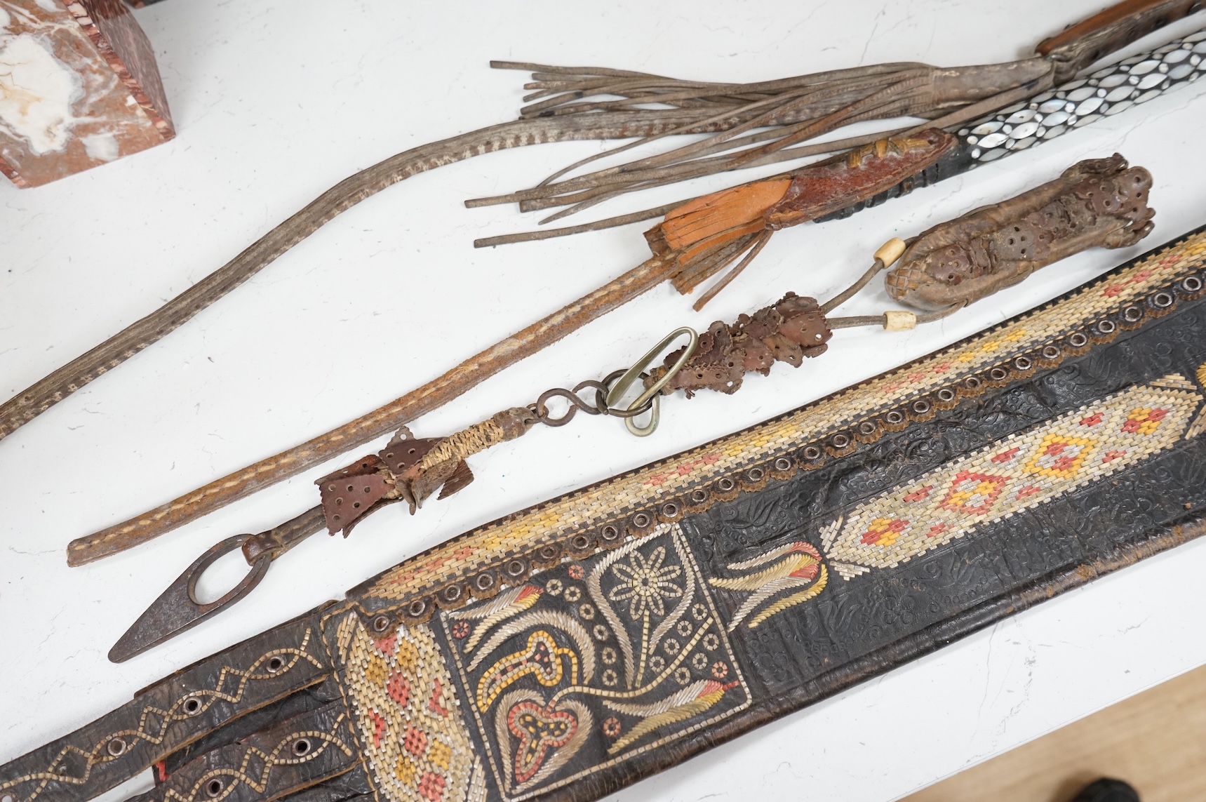 An Argentinian braided leather belt and whips, one with mother of pearl inlay